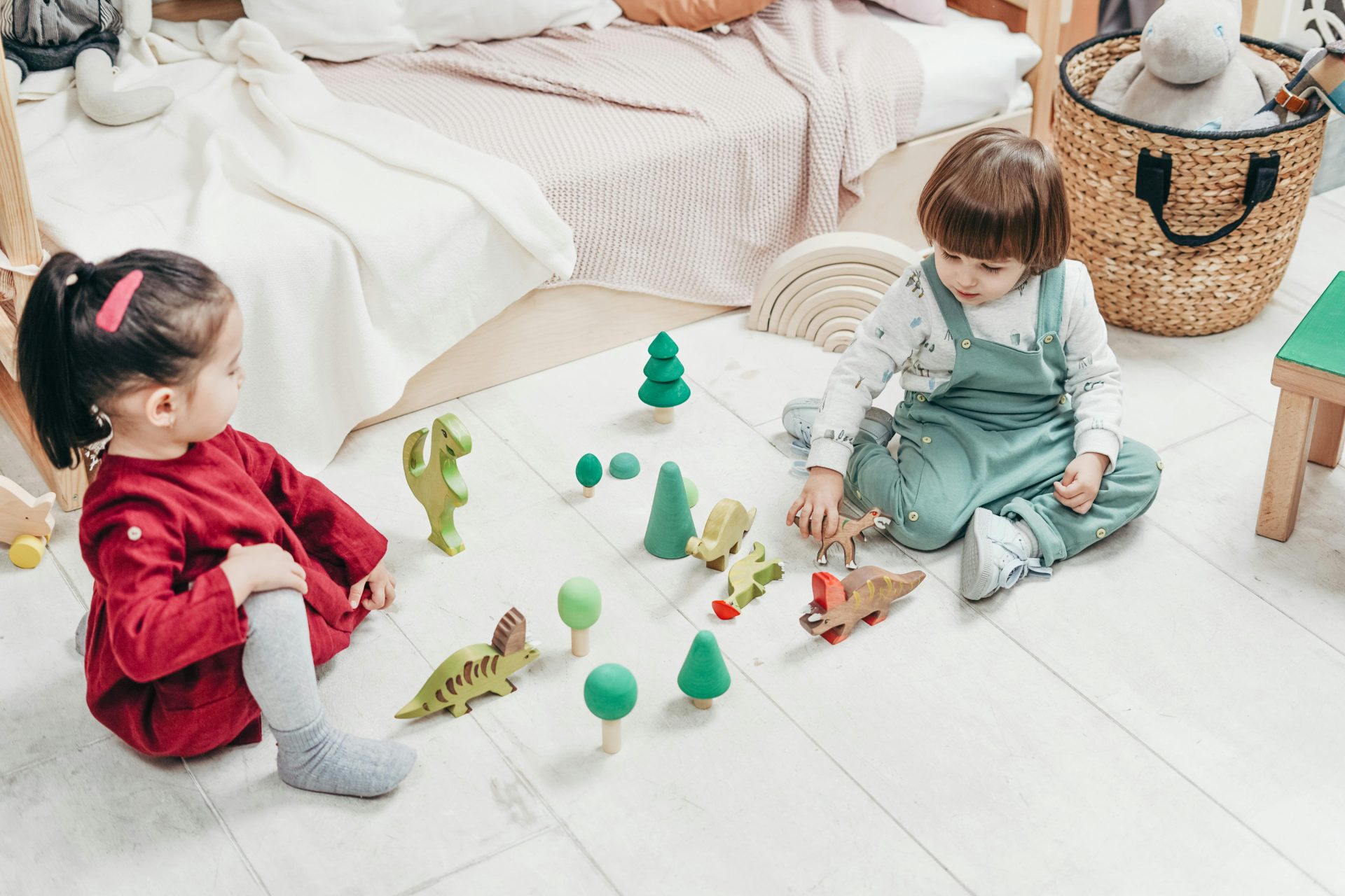 Two kids enjoying playtime with wooden toys in a cozy bedroom setting.