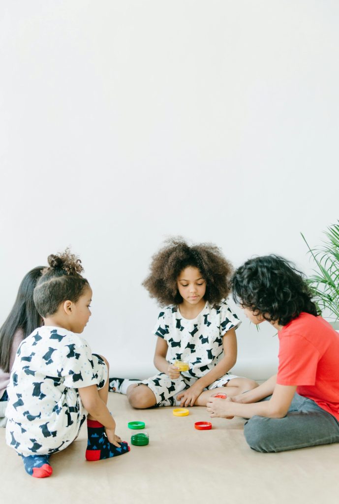 Four children enjoying a creative indoor playtime with paints and crafts in a bright setting.